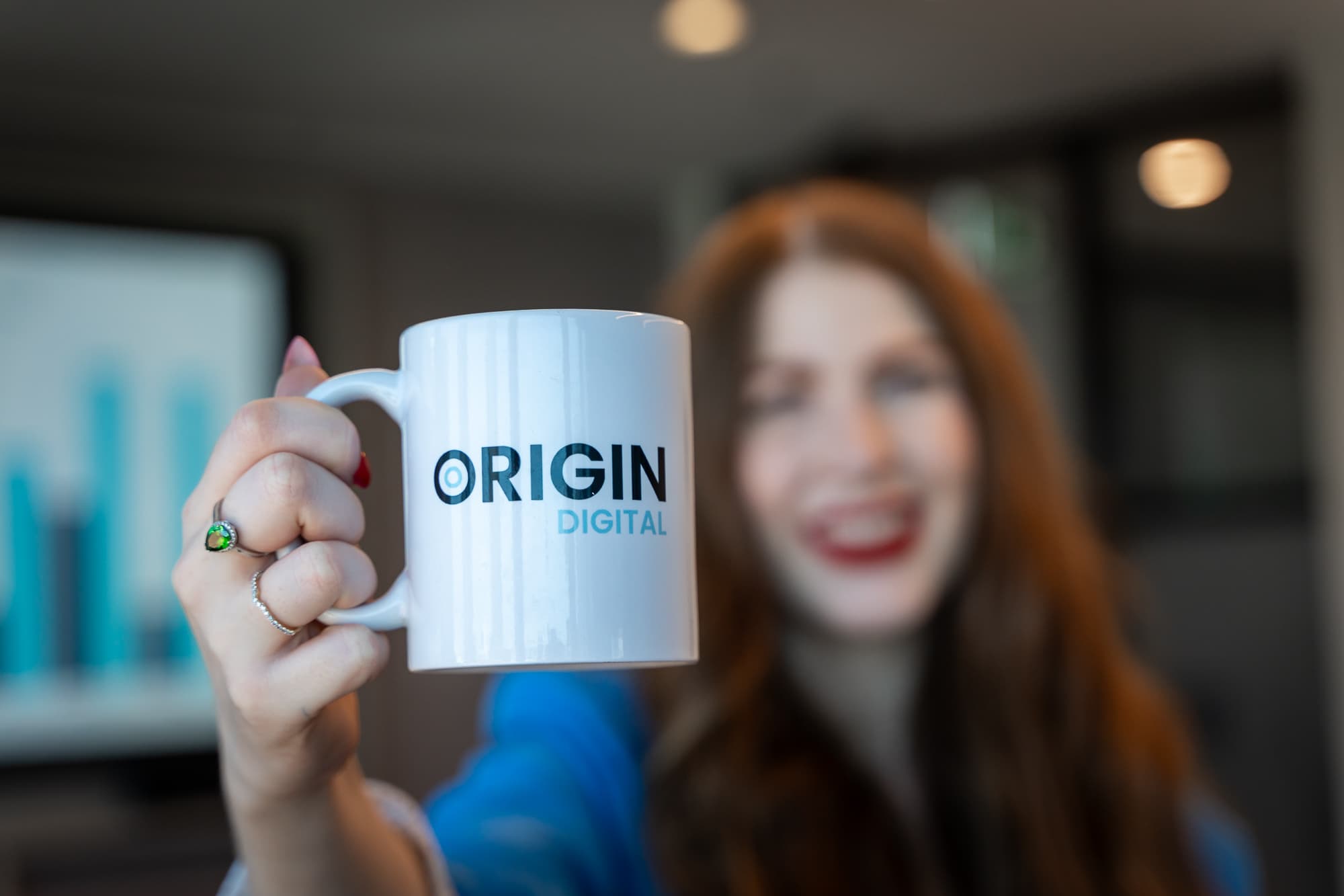 Woman holding Origin Digital mug for endpoint services